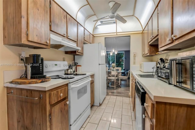 kitchen with white appliances, under cabinet range hood, a ceiling fan, light countertops, and brown cabinets