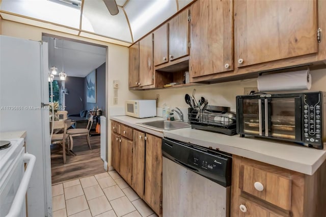 kitchen featuring stainless steel dishwasher, white microwave, a sink, stove, and light countertops