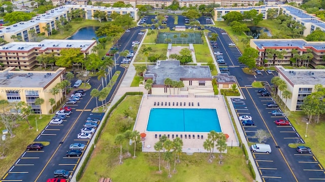 drone / aerial view of a pool, apartment complex, and a nearby body of water