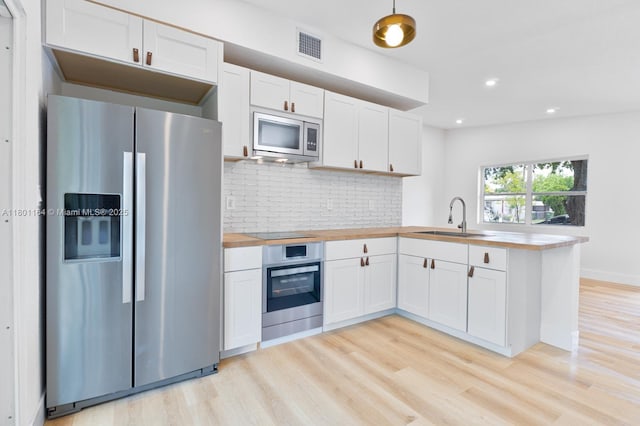 75 NW 125th St, North Miami, FL 33168 - kitchen with appliances with stainless steel finishes, a sink, a peninsula, butcher block countertops, and light wood-type flooring