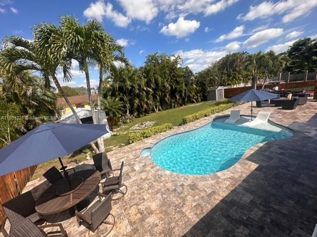 12821 SW 10th Ct, Davie, FL 33325 - swimming pool with a patio area, a storage unit, an outbuilding, and fence