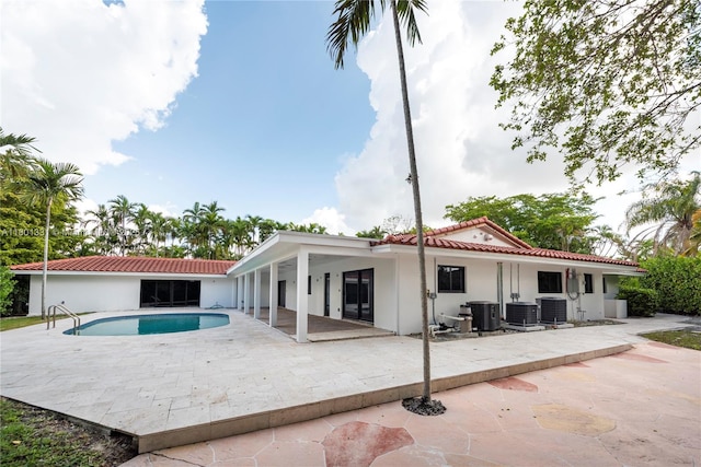 2800 Palmer Dr, Hollywood, FL 33021 - back of property featuring a patio area, a tiled roof, stucco siding, central AC unit, and an outdoor pool