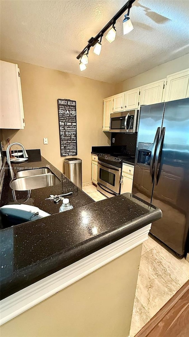 2665 SW 37th Ave Unit 1112, Miami, FL 33133 - kitchen featuring appliances with stainless steel finishes, a sink, dark stone counters, white cabinetry, and a textured ceiling