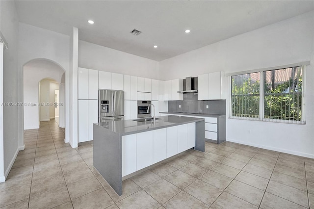 3360 SW 195th Ter, Miramar, FL 33029 - kitchen featuring appliances with stainless steel finishes, wall chimney exhaust hood, arched walkways, light tile patterned floors, and a kitchen island with sink