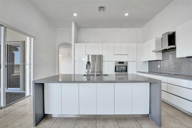 3360 SW 195th Ter, Miramar, FL 33029 - kitchen featuring stainless steel appliances, wall chimney exhaust hood, arched walkways, white cabinets, and a spacious island