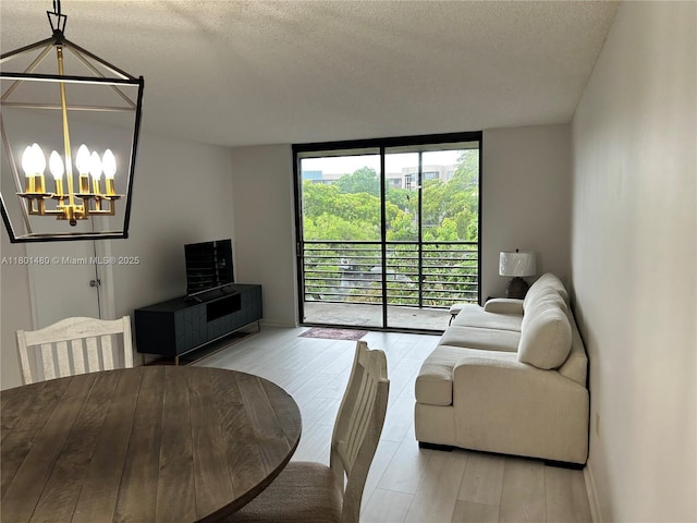 1000 Colony Point Cir Unit 302, Pembroke Pines, FL 33026 - living area with a chandelier, a wall of windows, a textured ceiling, wood finished floors, and baseboards