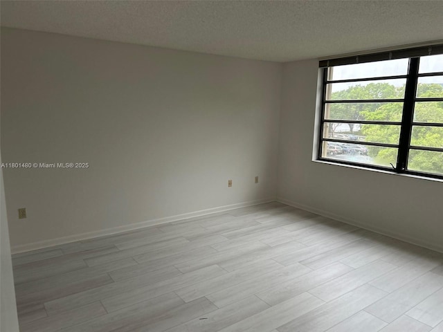 1000 Colony Point Cir Unit 302, Pembroke Pines, FL 33026 - empty room with a textured ceiling, light wood-style flooring, and baseboards