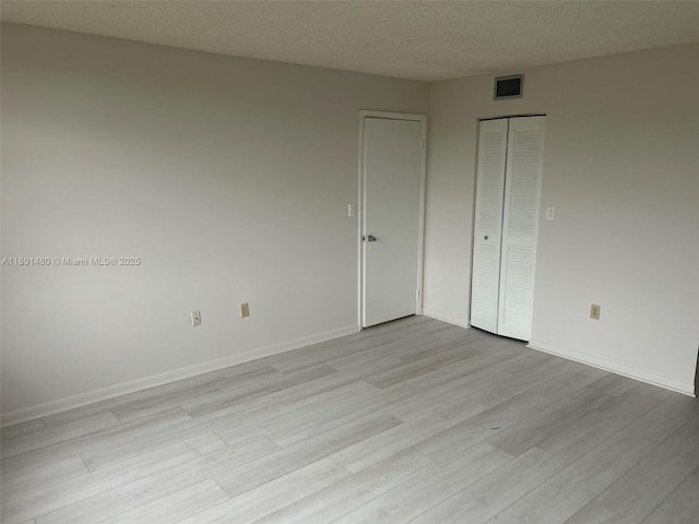 1000 Colony Point Cir Unit 302, Pembroke Pines, FL 33026 - unfurnished bedroom with light wood-style flooring, baseboards, a closet, and a textured ceiling