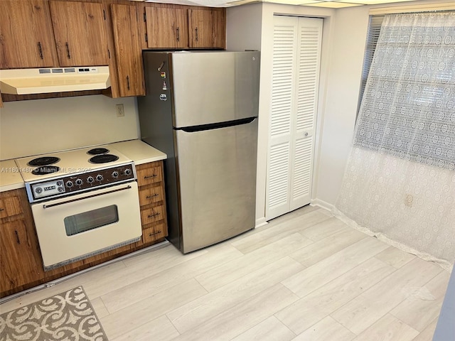 1000 Colony Point Cir Unit 302, Pembroke Pines, FL 33026 - kitchen featuring under cabinet range hood, freestanding refrigerator, white electric stove, light wood-style flooring, and brown cabinetry