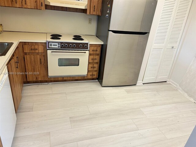 1000 Colony Point Cir Unit 302, Pembroke Pines, FL 33026 - kitchen with white appliances, brown cabinetry, exhaust hood, light countertops, and light wood-style flooring