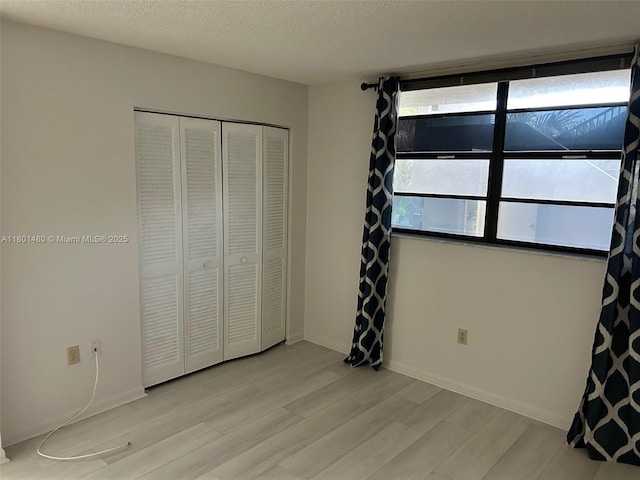 1000 Colony Point Cir Unit 302, Pembroke Pines, FL 33026 - unfurnished bedroom featuring light wood finished floors, a closet, and a textured ceiling