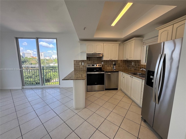 3500 Coral Way Unit 501, Miami, FL 33145 - kitchen with stainless steel appliances, a peninsula, a tray ceiling, backsplash, and light tile patterned floors
