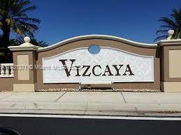 community sign with an attached garage and driveway