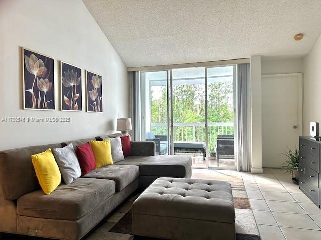 4632 NW 97th Pl Unit 262, Doral, FL 33178 - living area featuring a textured ceiling, expansive windows, light tile patterned floors, and lofted ceiling