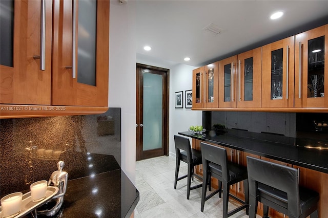 1530 NE Quayside Ter Unit A1, Miami, FL 33138 - kitchen featuring decorative backsplash, glass insert cabinets, recessed lighting, dark stone counters, and baseboards