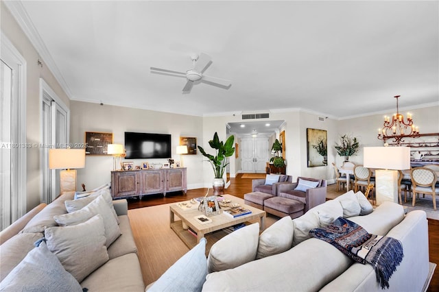 living area featuring a chandelier, wood finished floors, ornamental molding, a ceiling fan, and baseboards
