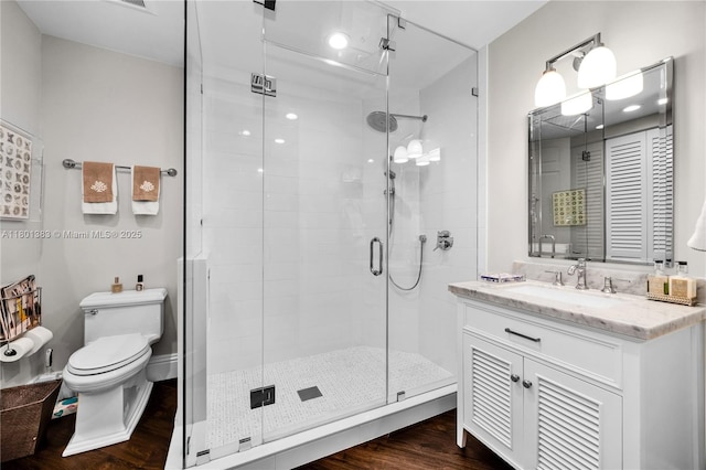 bathroom featuring a shower stall, toilet, vanity, and wood finished floors