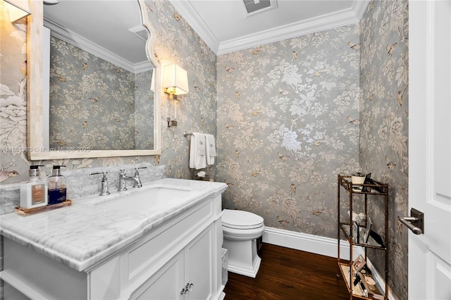 half bath with hardwood / wood-style floors, toilet, baseboards, vanity, and ornamental molding