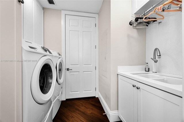 laundry area with independent washer and dryer, dark wood-type flooring, cabinet space, and baseboards
