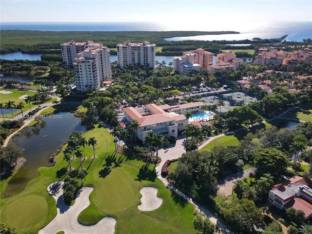 view of property location featuring apartment complex / building, a nearby body of water, and a golf course