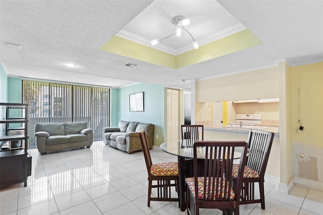 dining space featuring a textured ceiling, a tray ceiling, crown molding, light tile patterned floors, and baseboards