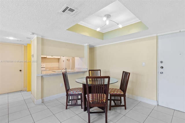 dining space with a raised ceiling, ornamental molding, a textured ceiling, light tile patterned flooring, and baseboards