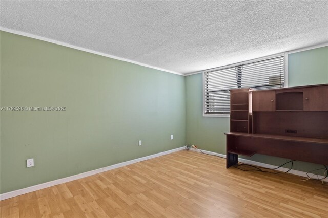 unfurnished room with wood finished floors, a textured ceiling, and baseboards