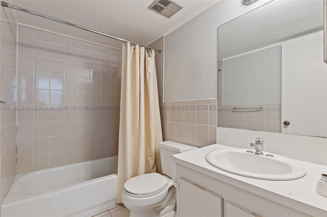 full bathroom featuring toilet, shower / bath combo with shower curtain, vanity, and tile walls