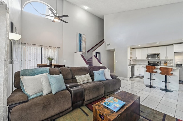 2323 NW 37th Ave, Coconut Creek, FL 33066 - living area featuring high vaulted ceiling, ceiling fan, stairs, healthy amount of natural light, and light tile patterned flooring