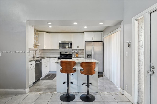 2323 NW 37th Ave, Coconut Creek, FL 33066 - kitchen with appliances with stainless steel finishes, white cabinets, decorative backsplash, light stone counters, and a kitchen island