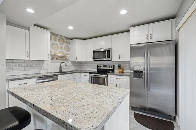 2323 NW 37th Ave, Coconut Creek, FL 33066 - kitchen with appliances with stainless steel finishes, light stone counters, white cabinetry, backsplash, and recessed lighting