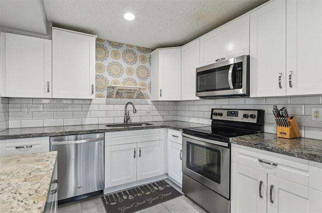 2323 NW 37th Ave, Coconut Creek, FL 33066 - kitchen with stainless steel appliances, white cabinets, a textured ceiling, dark stone counters, and tasteful backsplash