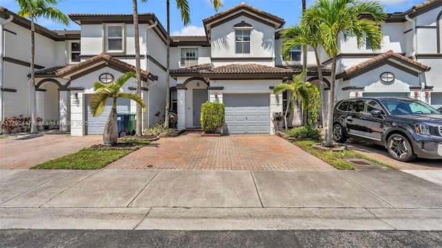 view of front of house with a tiled roof, stucco siding, decorative driveway, and an attached garage