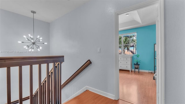 stairway featuring wood finished floors, baseboards, and a chandelier
