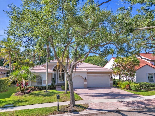 2623 Oakbrook Dr, Weston, FL 33332 - view of front facade with a front yard, a garage, decorative driveway, stucco siding, and a tiled roof