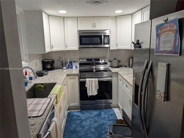 kitchen featuring stainless steel appliances, a sink, white cabinetry, and decorative backsplash