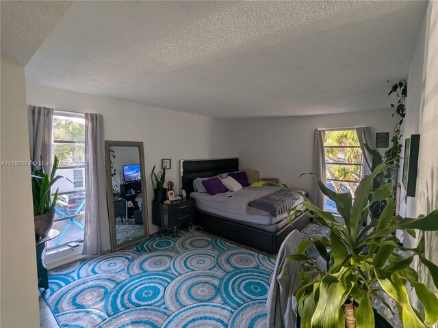 carpeted bedroom featuring a textured ceiling and multiple windows