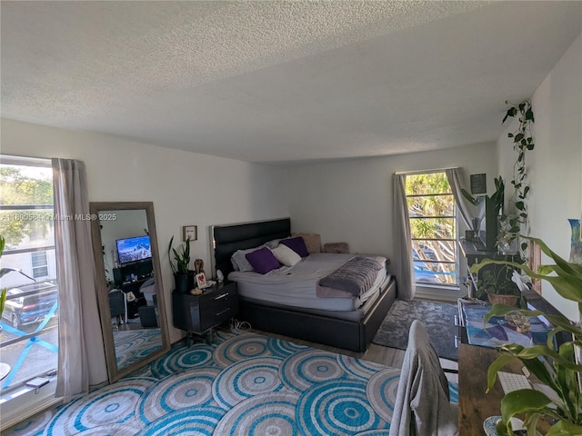bedroom with a textured ceiling and multiple windows