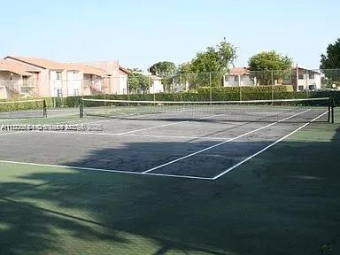 view of tennis court with a residential view and fence