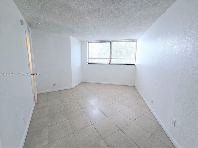 1850 N Congress Ave Unit 311, West Palm Beach, FL 33401 - unfurnished room with a textured ceiling, light tile patterned flooring, and baseboards