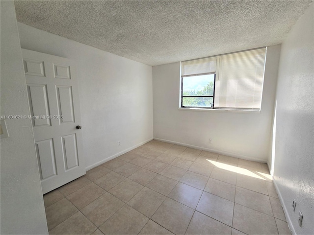 1850 N Congress Ave Unit 311, West Palm Beach, FL 33401 - spare room with a textured ceiling, light tile patterned floors, and baseboards