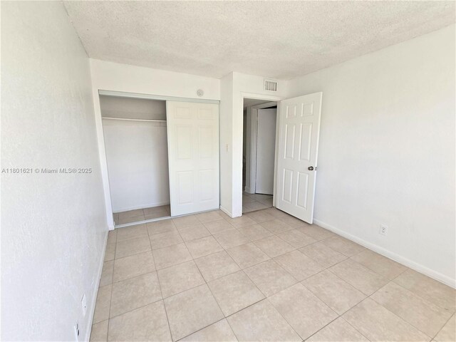 1850 N Congress Ave Unit 311, West Palm Beach, FL 33401 - unfurnished bedroom with a textured ceiling, light tile patterned floors, a closet, and baseboards