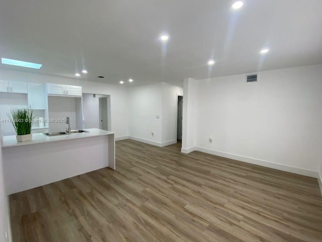 22011 Catherine Prt, Charlotte, FL 33952 - unfurnished living room with a sink, recessed lighting, light wood-style flooring, baseboards, and a skylight
