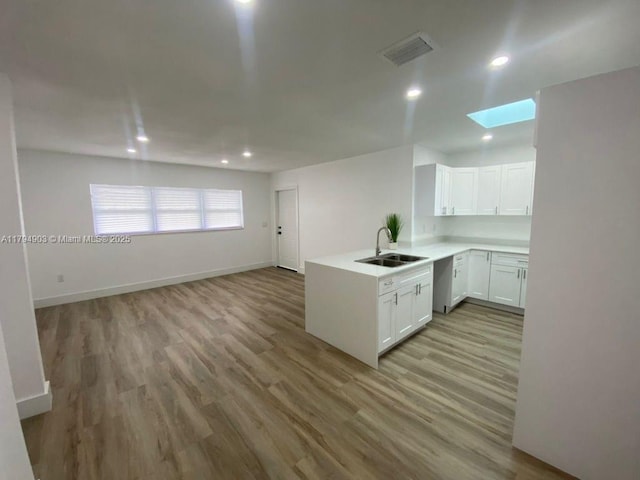 22011 Catherine Prt, Charlotte, FL 33952 - kitchen featuring a sink, a skylight, a peninsula, white cabinetry, and recessed lighting