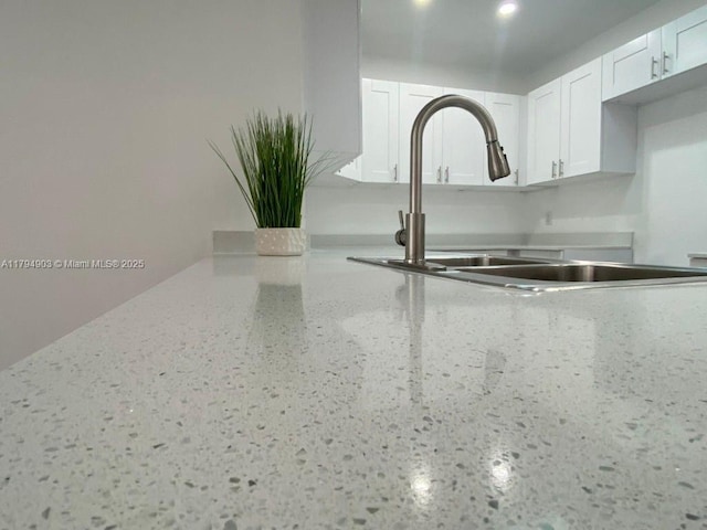 22011 Catherine Prt, Charlotte, FL 33952 - kitchen view of a sink, white cabinetry, and light stone counters