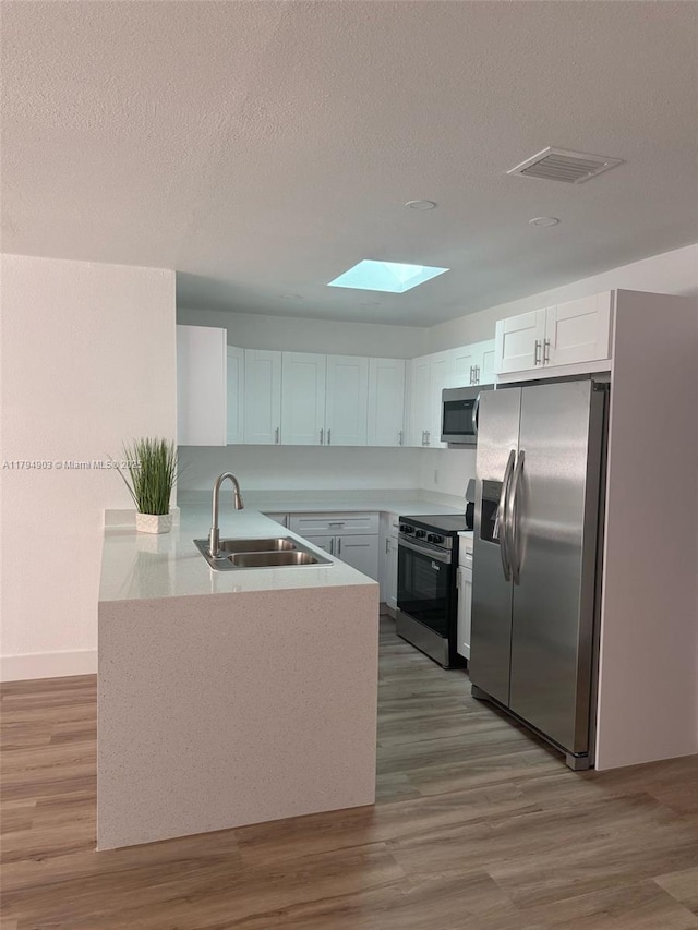 22011 Catherine Prt, Charlotte, FL 33952 - kitchen featuring stainless steel appliances, a sink, a skylight, a peninsula, and a textured ceiling