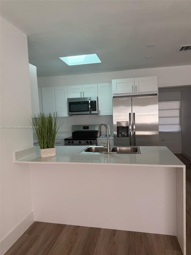 22011 Catherine Prt, Charlotte, FL 33952 - kitchen featuring stainless steel appliances, a skylight, a sink, dark wood-style flooring, and baseboards