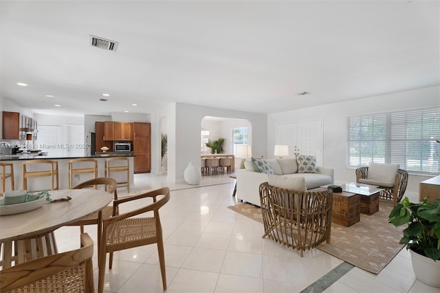 living room featuring arched walkways, light tile patterned flooring, recessed lighting, and baseboards