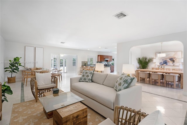 living room featuring light tile patterned flooring, arched walkways, and recessed lighting