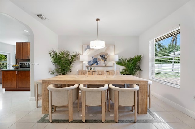 dining area with arched walkways, plenty of natural light, baseboards, and light tile patterned floors